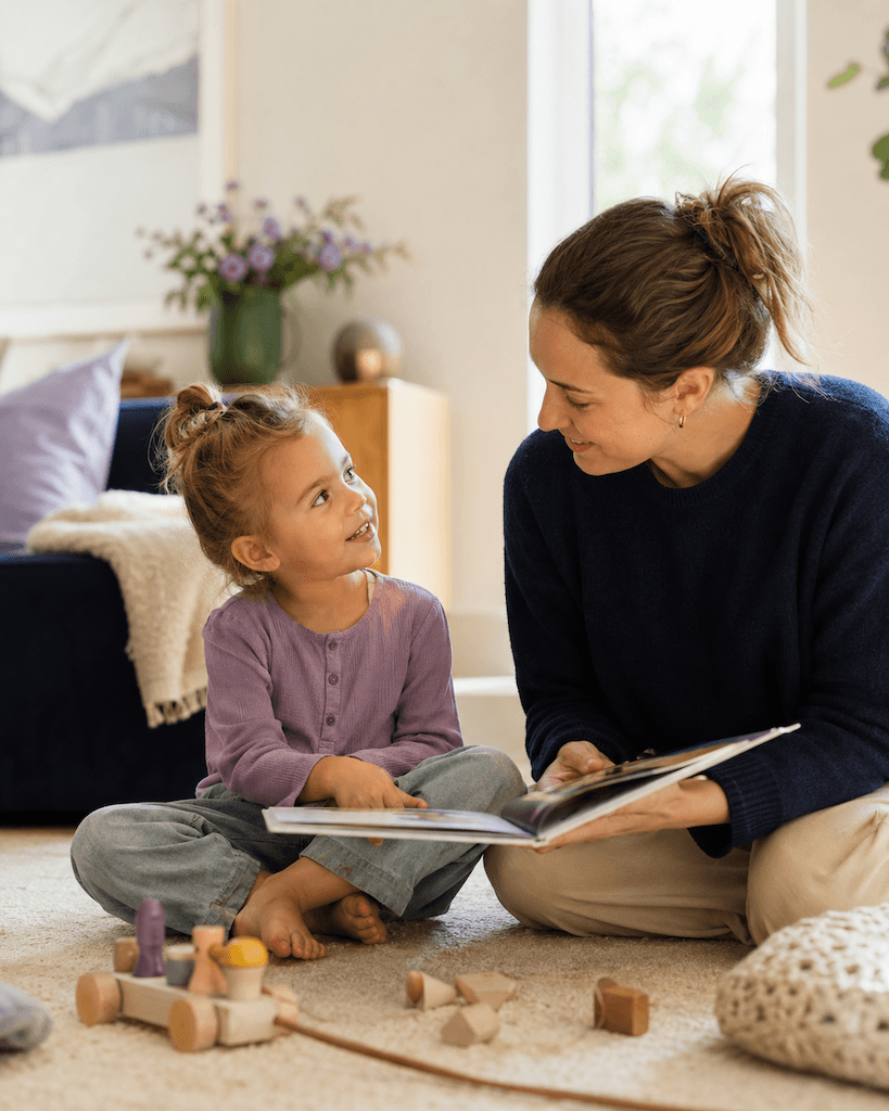 Elternteil spricht und spielt mit einem Vorschulkind in einer alltäglichen Sprachfördersituation zu Hause (KI-generiert)