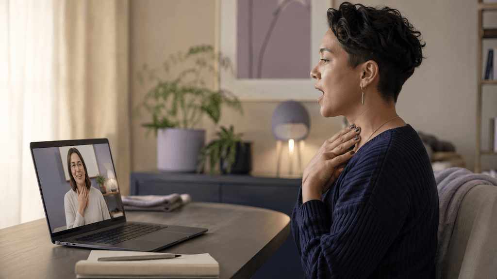 Trans Person nimmt diskret aus der vertrauten Umgebung zu Hause an einer geschlechtsangleichenden Online-Stimmtherapie teil (KI-generiert)